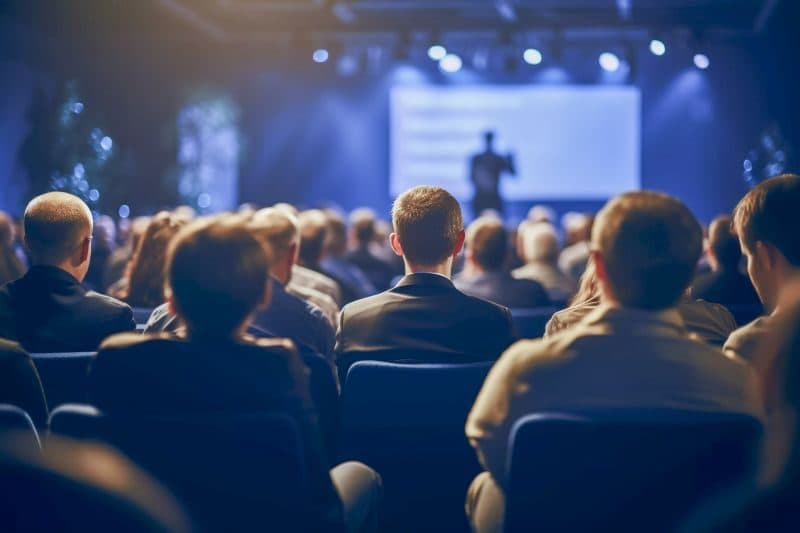 Audience at a large conference watching a presentation on stage