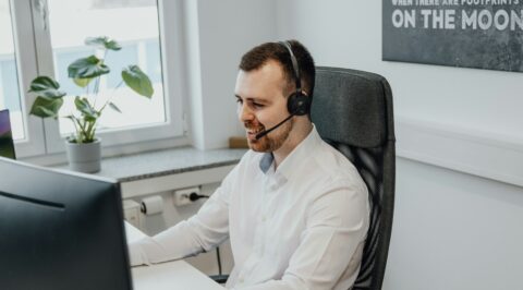 a man wearing a headset sitting in front of a computer {{brizy_dc_image_alt imageSrc=